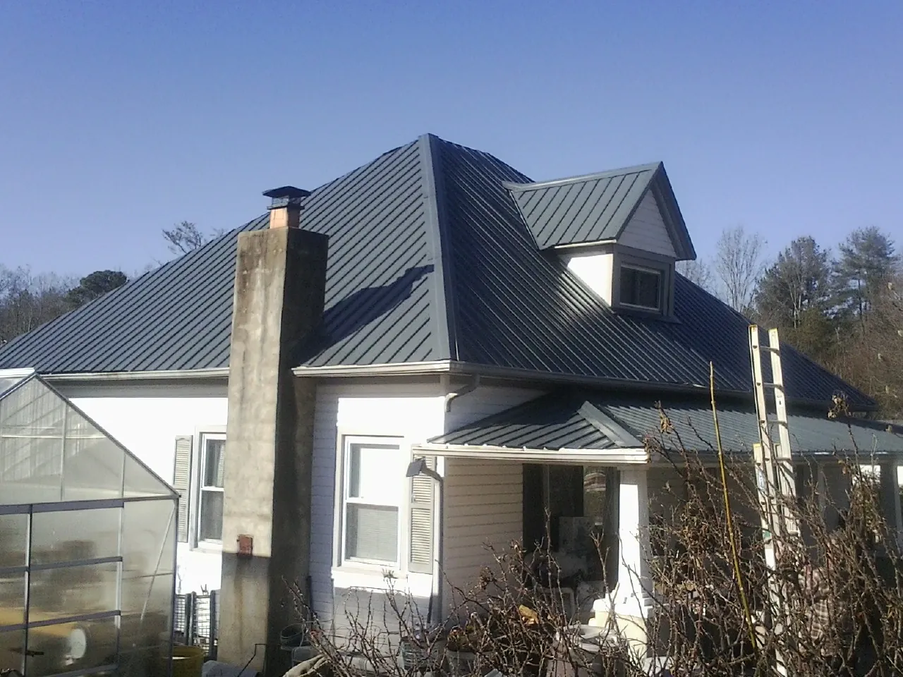 Dark blue standing seam metal roof on a white farmhouse with dormer — Slate & Tile Roof Repair by Roofing Brothers in Rifton