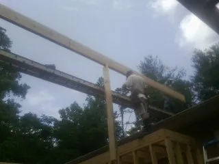 Carpenter setting a ridge beam over a new addition frame — Ice Dam Removal by Roofing Brothers in Rifton