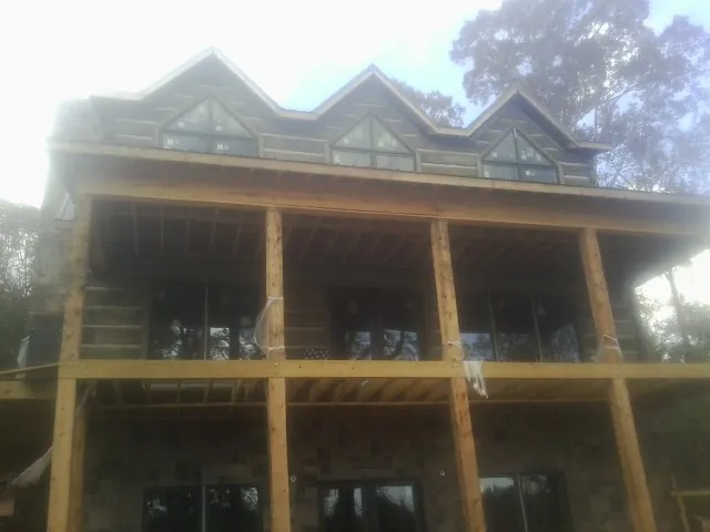 Dormers and porch framing on a large log home under construction — Roof Coating work by our crew in Rifton