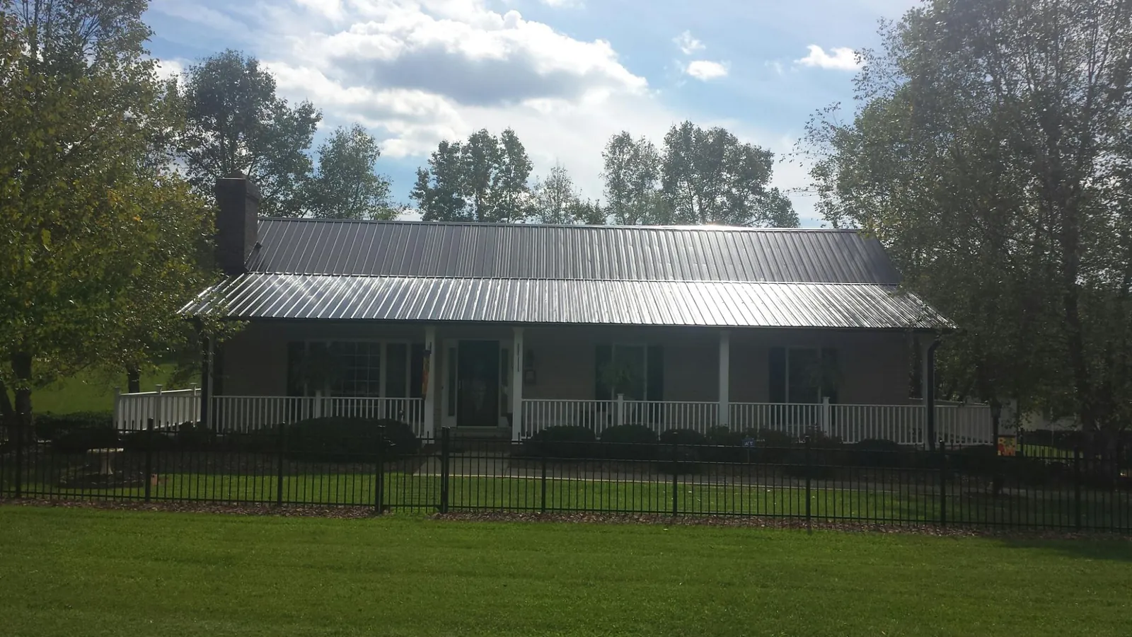 Gray metal roof on a brick ranch with a full width front porch — Gutter Guard Installation work by our crew in Rifton