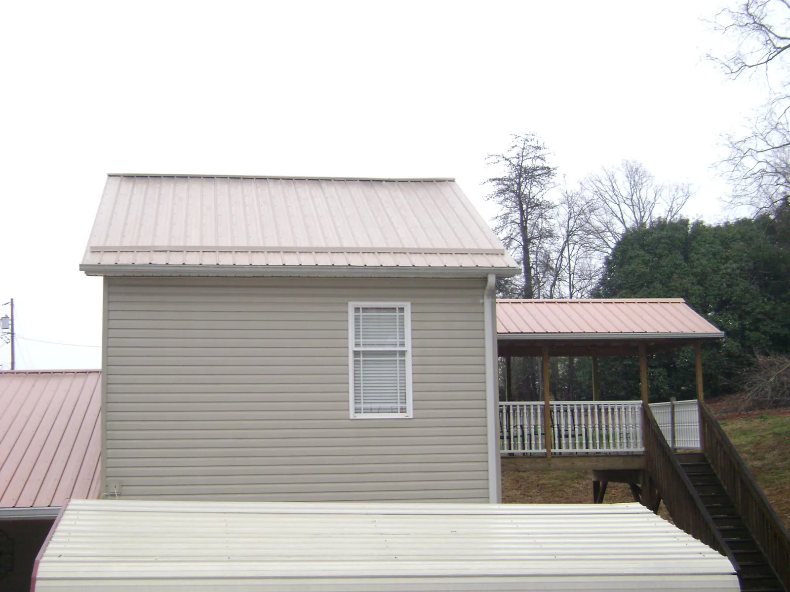 Tan metal roofs on a two story addition and attached porch, from a Roof Replacement job in Rifton