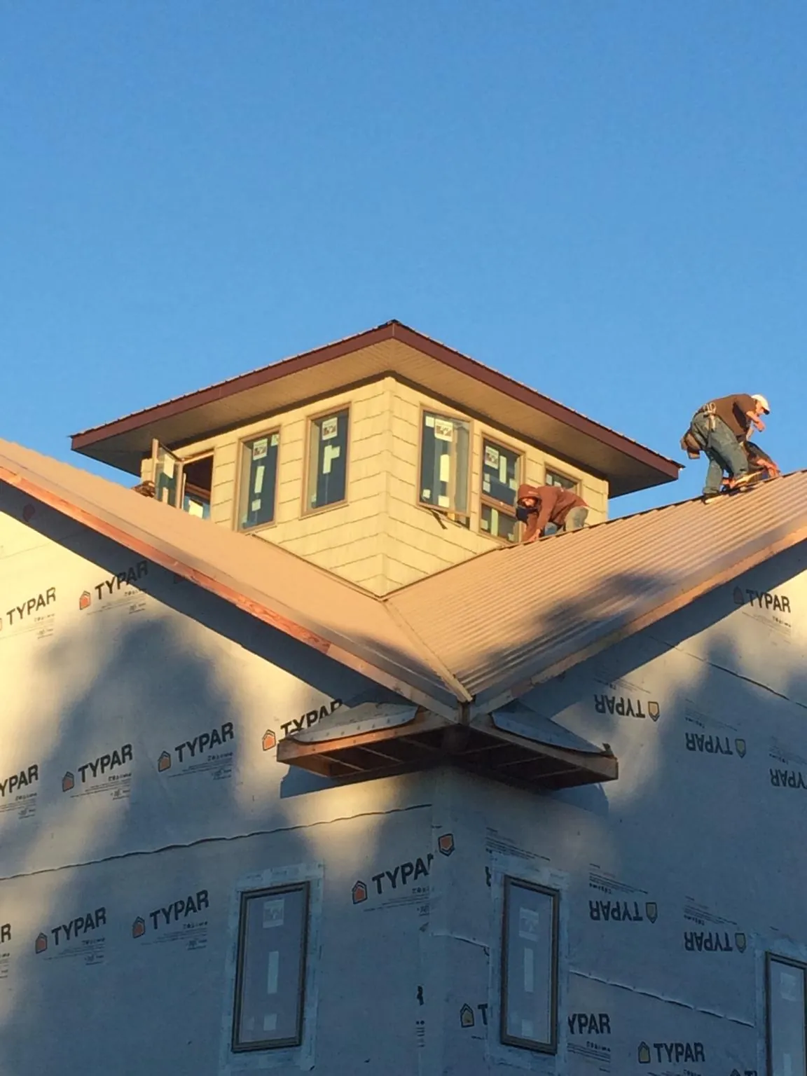 Roofers working around a rooftop cupola on a new metal roof at sunset — Roof Waterproofing in Rifton by Roofing Brothers